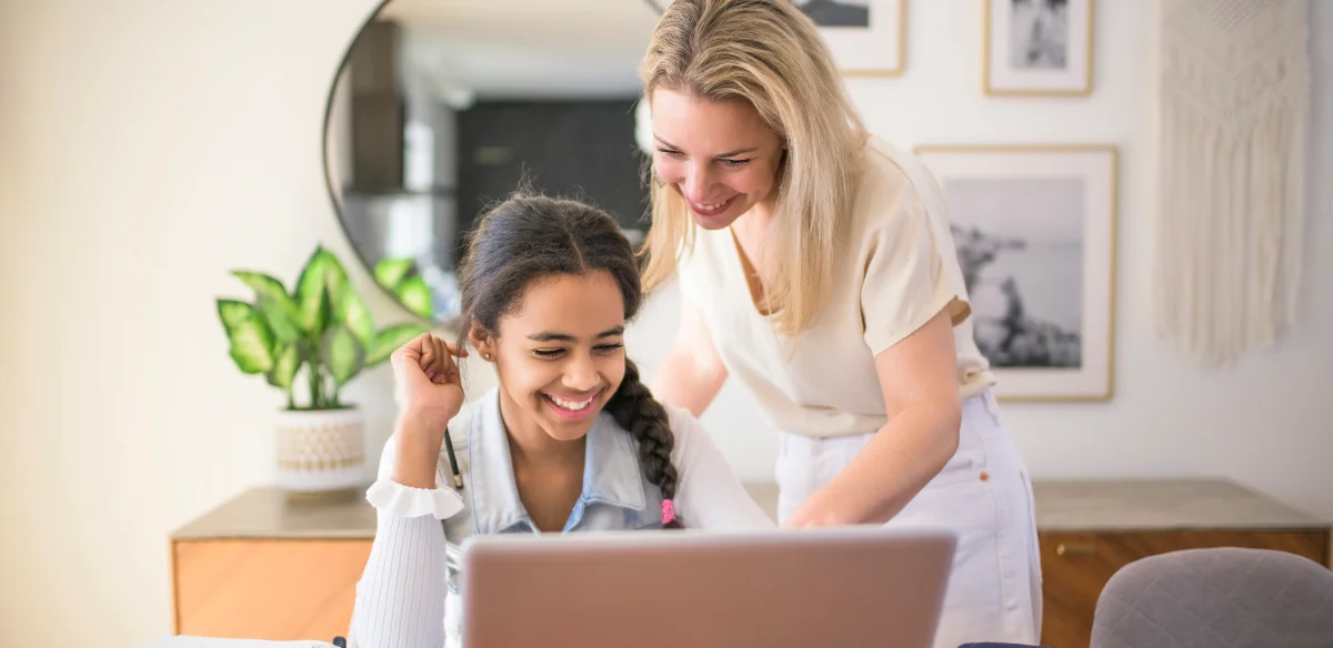 Mother and daughter working together with their laptop at home